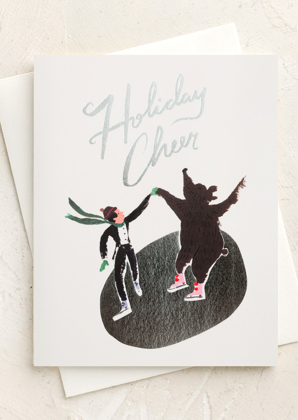 A set of cards depicting an ice skater and bear skating on silver pond, text reads "Holiday cheer".