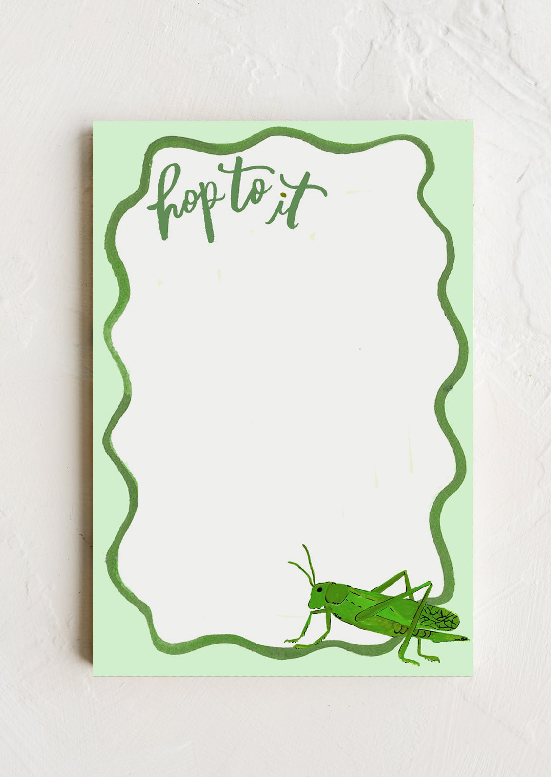 A notepad with wavy green border, text at corner reads "Hop to it", grasshopper illustration at other end.