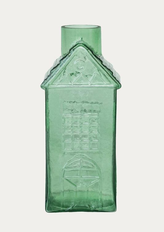 A glass vase in the shape of a house in green.