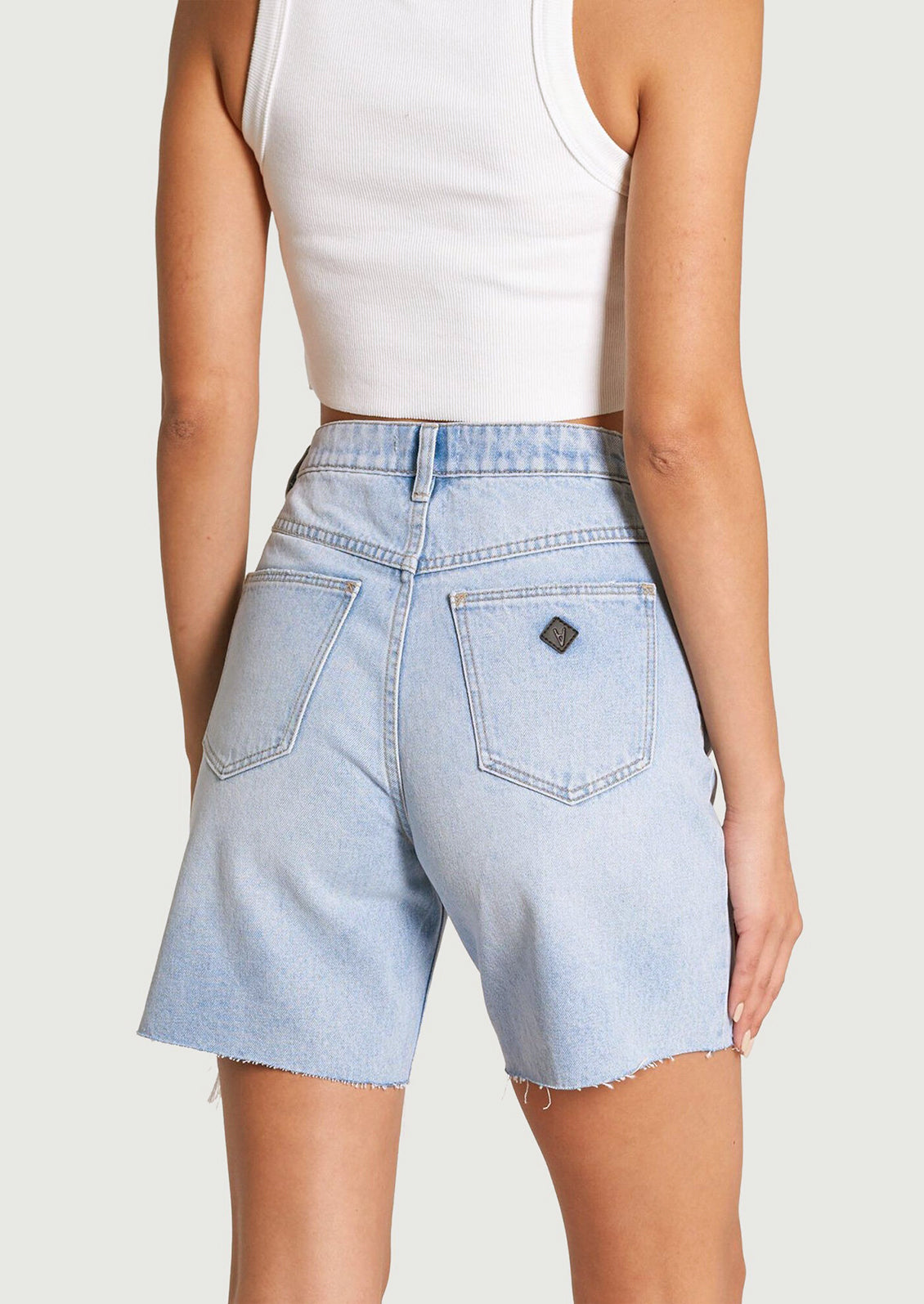 A pair of light blue denim shorts with mid-length and distressed detailing at hemline.