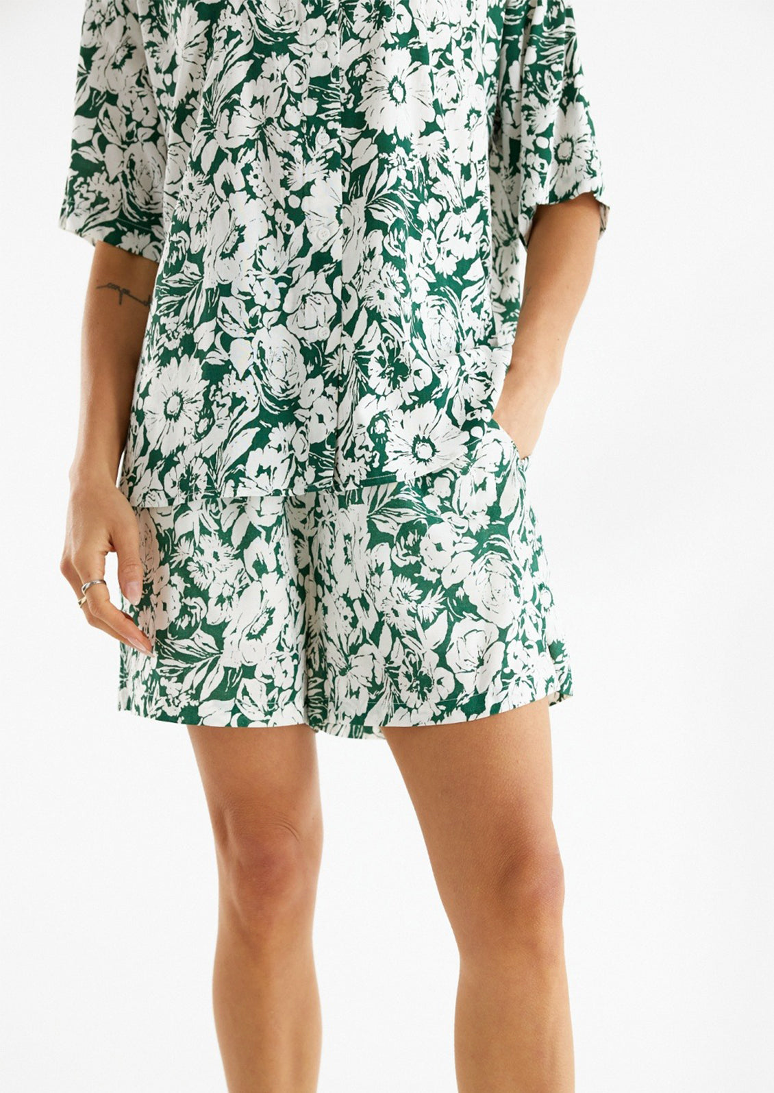 Woman wearing green and white floral printed shorts. 