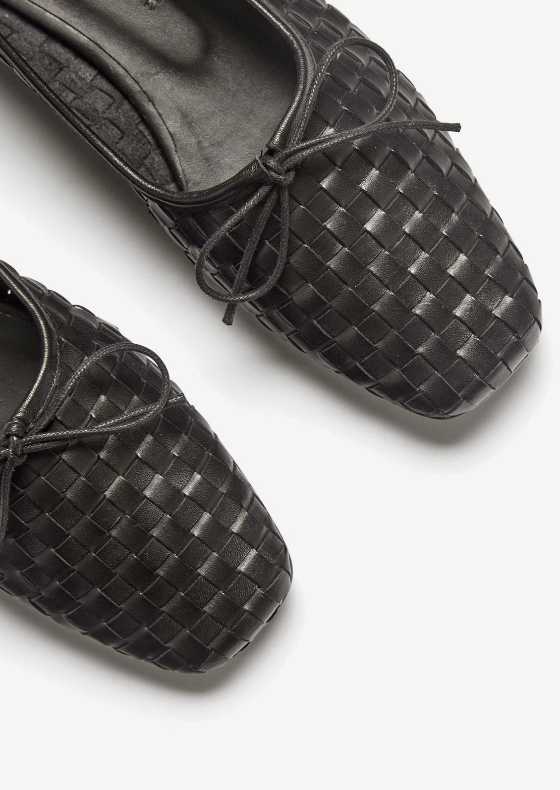 A pair of square toe ballet flats with bow tie in black woven leather.