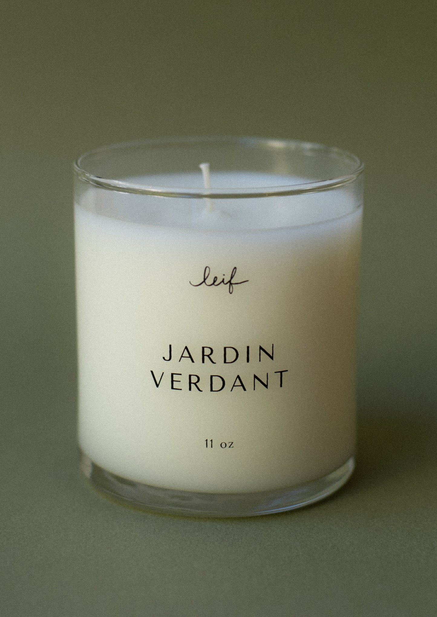 A candle in clear glass jar labeled "Jardin Verdant".