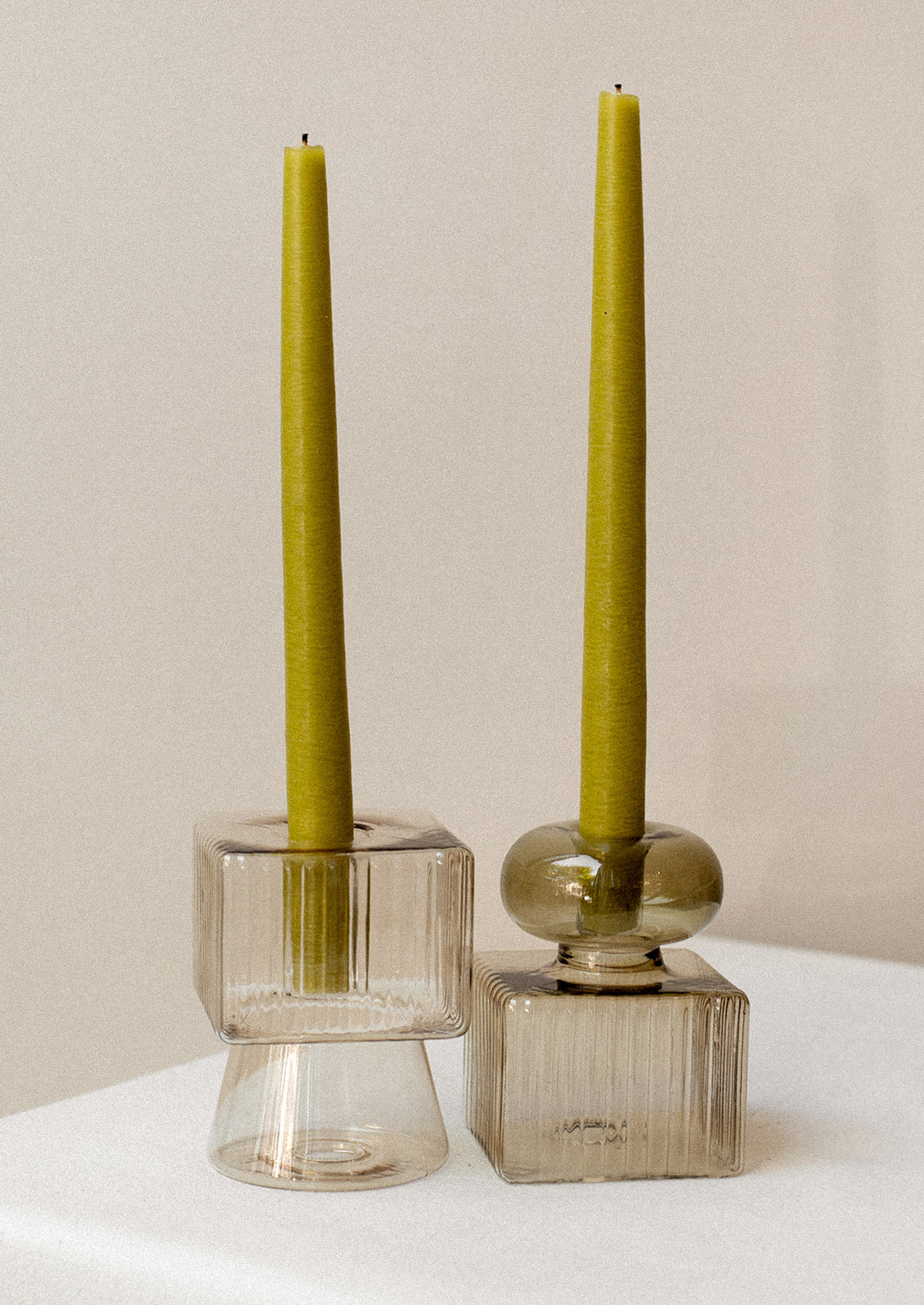 Transparent glass candleholders in mixed geometric shape with ribbing texture.