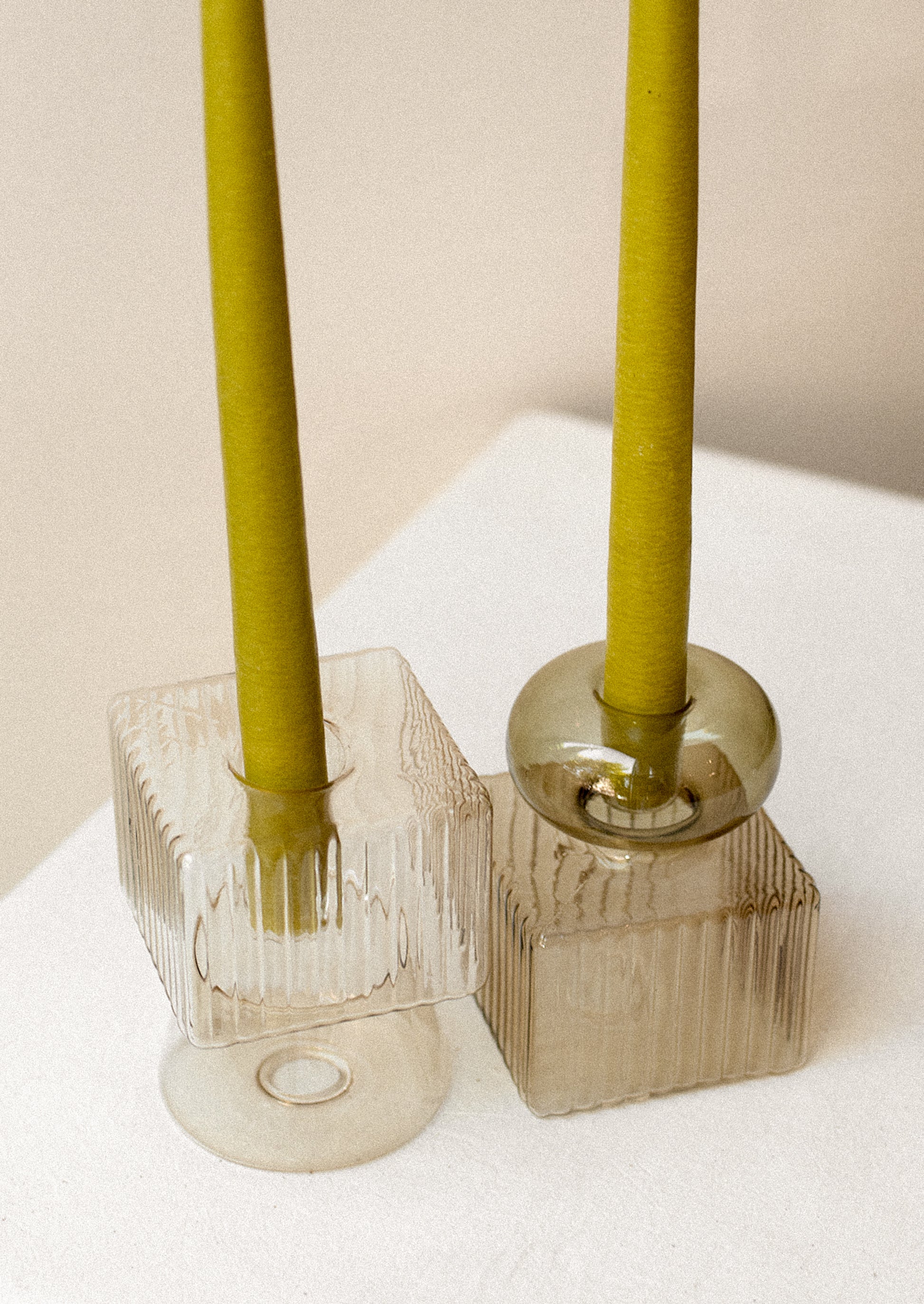 Transparent glass candleholders in mixed geometric shape with ribbing texture.