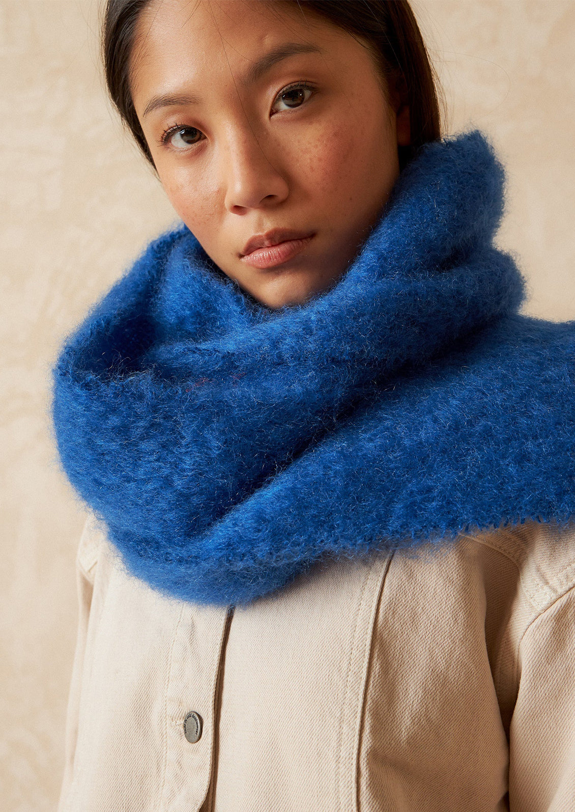 A woman wearing a fuzzy mohair scarf in cobalt blue.