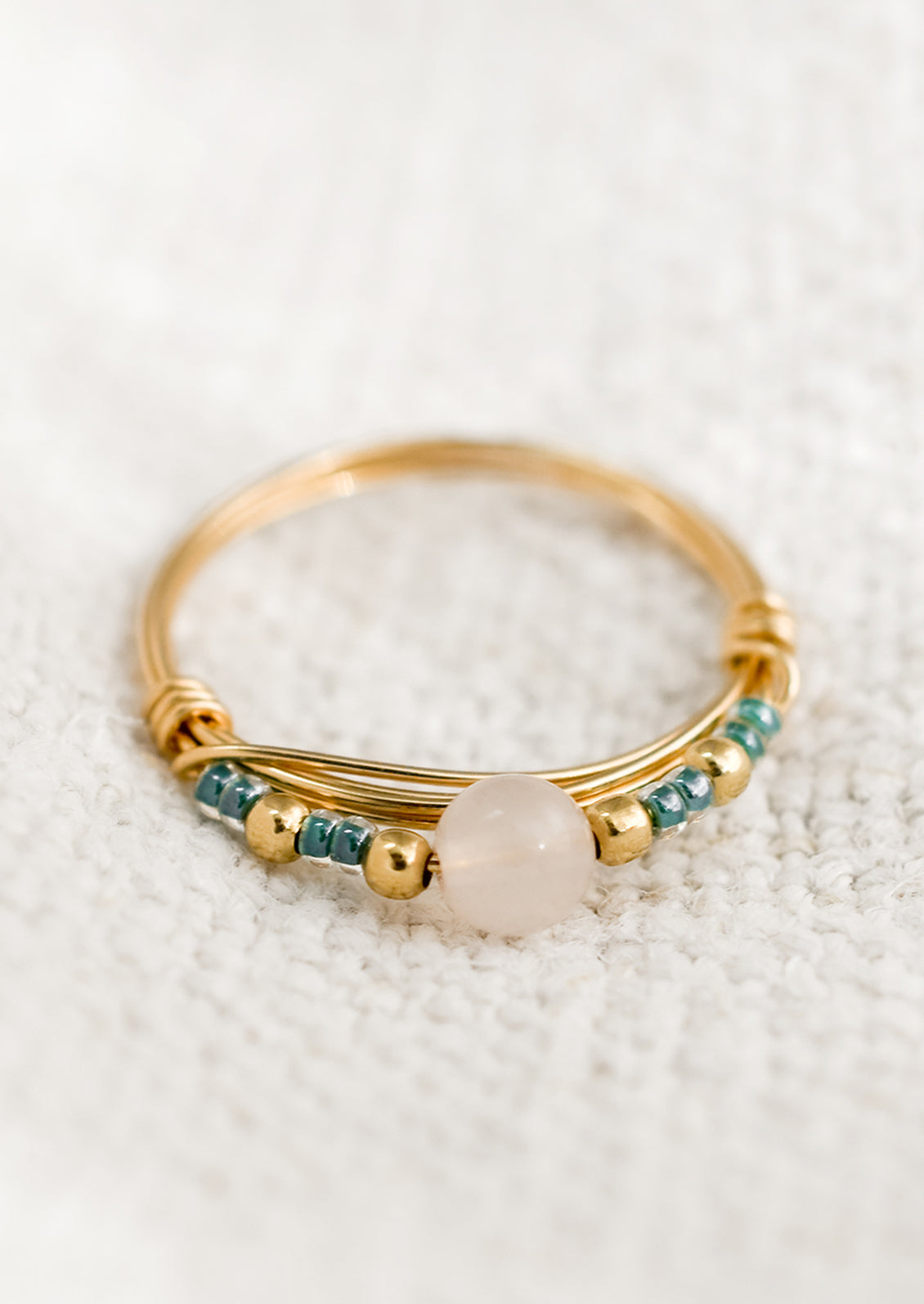 A gold wire ring with blue and pink beads.