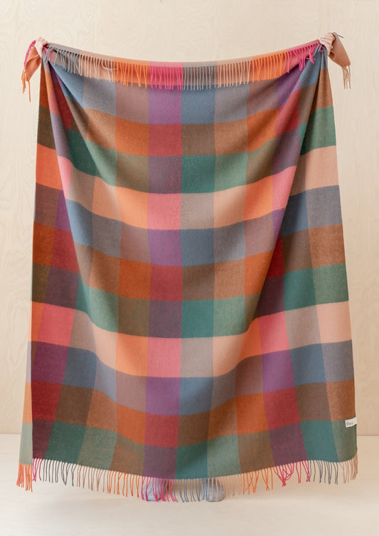 A madras check print wool throw in shades of peach, pink, teal, orange and blue.