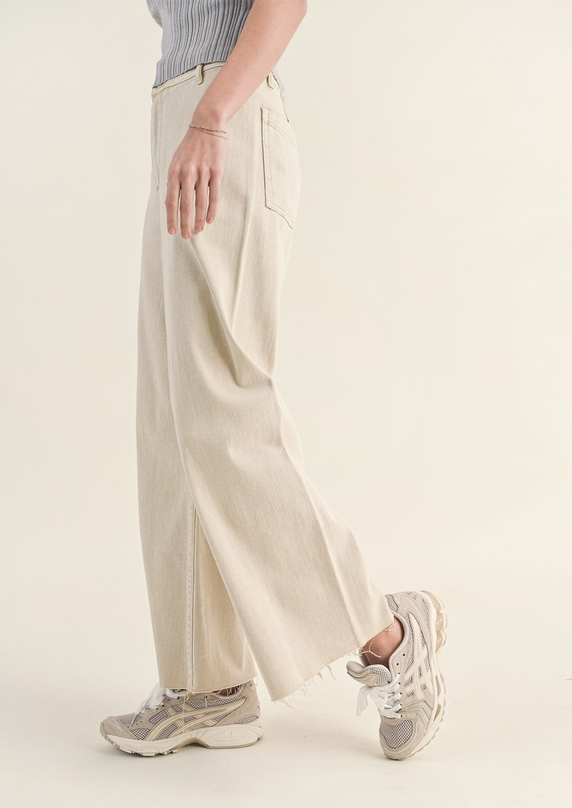 A pair of beige colored wide leg pants with belt loops.