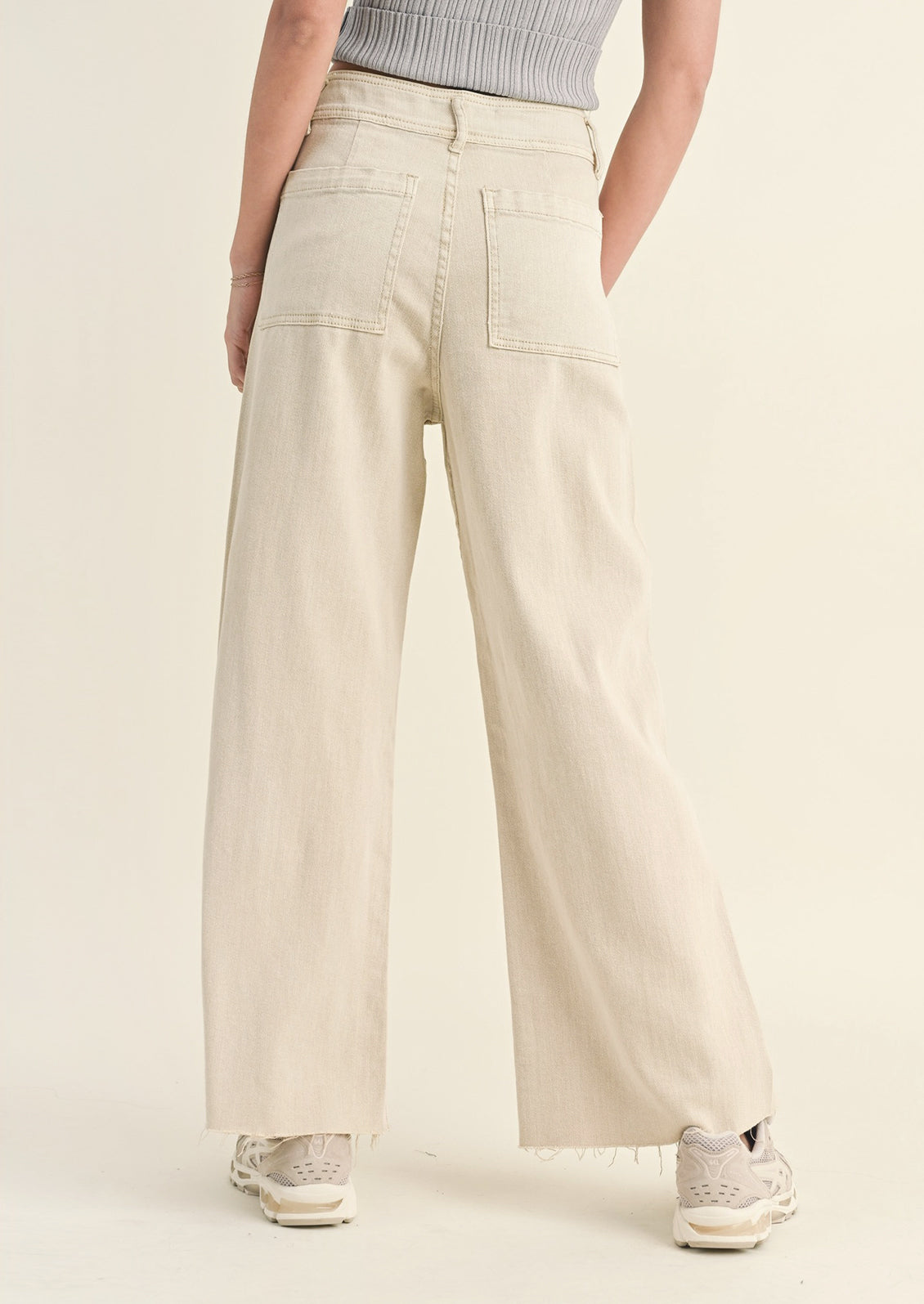 A pair of beige colored wide leg pants with back pockets.