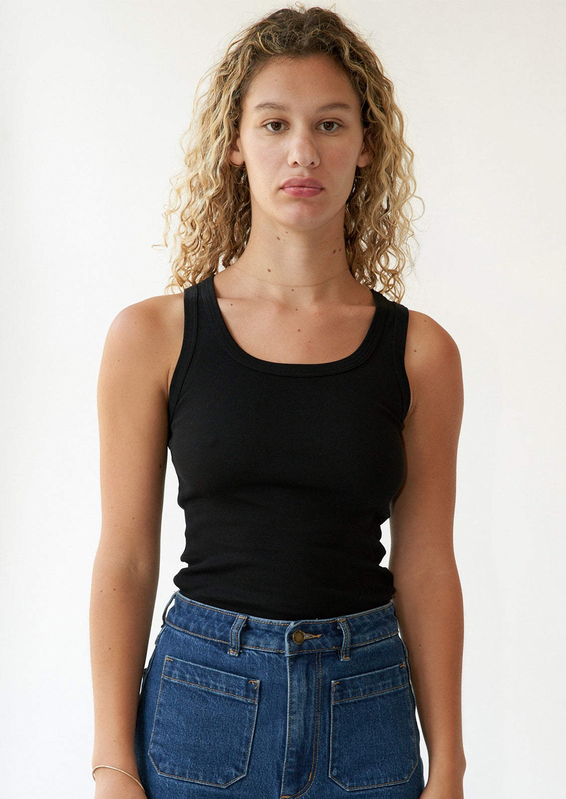 A woman wearing a classic tank top in black with scoop neck.