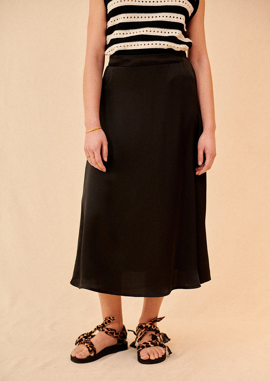 Woman wearing black midi skirt and sandals. 