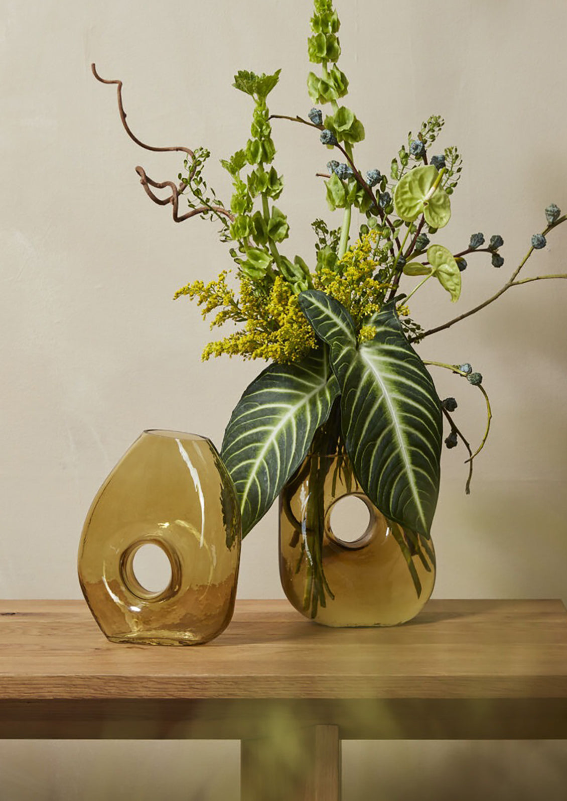 An asymmetrical, transparent green glass vase with cutout circle at center.