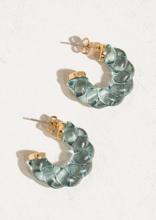 A pair of transparent lucite hoop earrings with spiral twist texture in light blue.