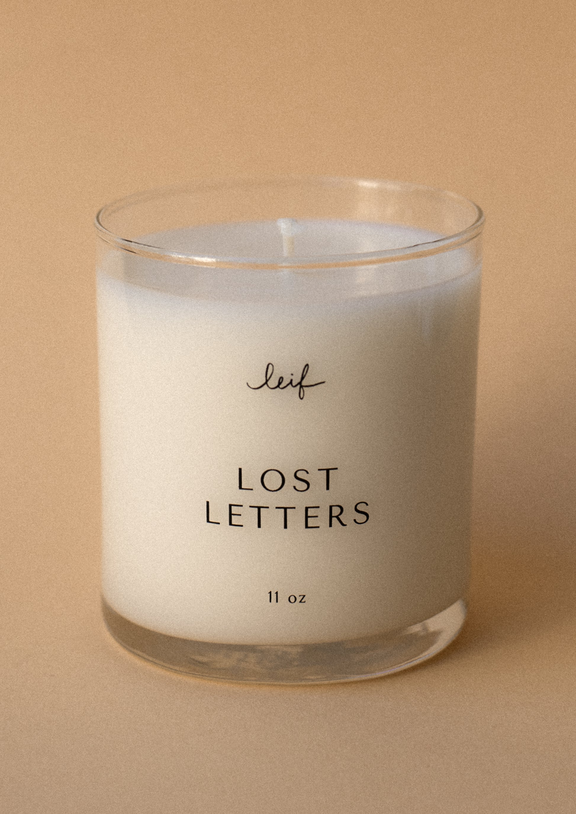 A candle in clear glass jar labeled "Lost Letters".