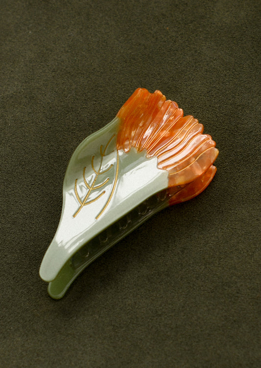 A green and orange hair claw in the shape of a marigold flower.