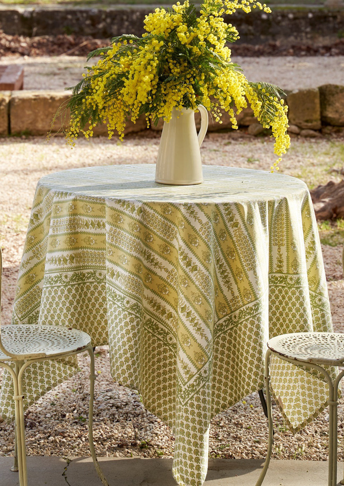 A block printed botanical patterned tablecloth in pastel yellow and green tones.