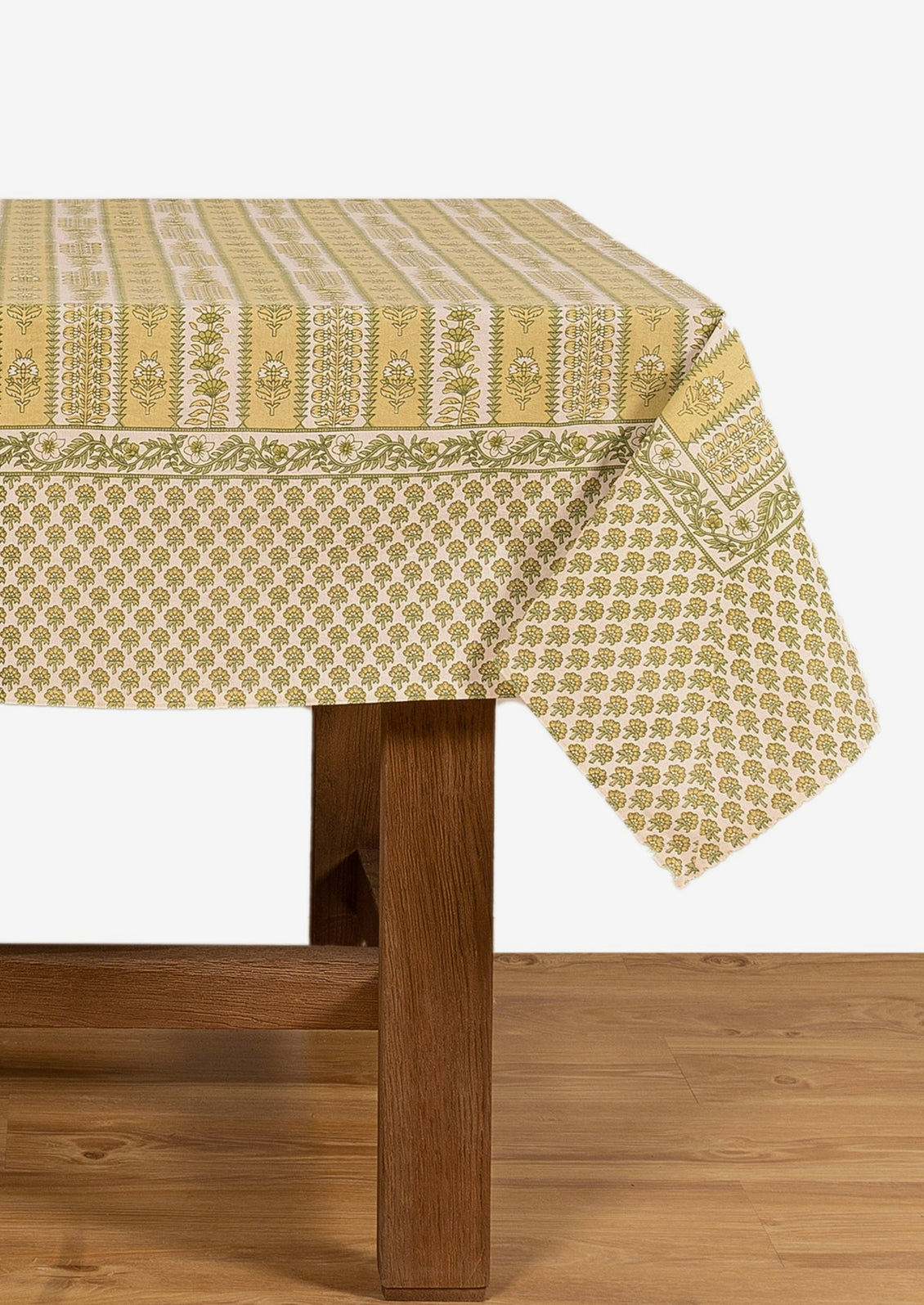 A block printed botanical patterned tablecloth in pastel yellow and green tones.