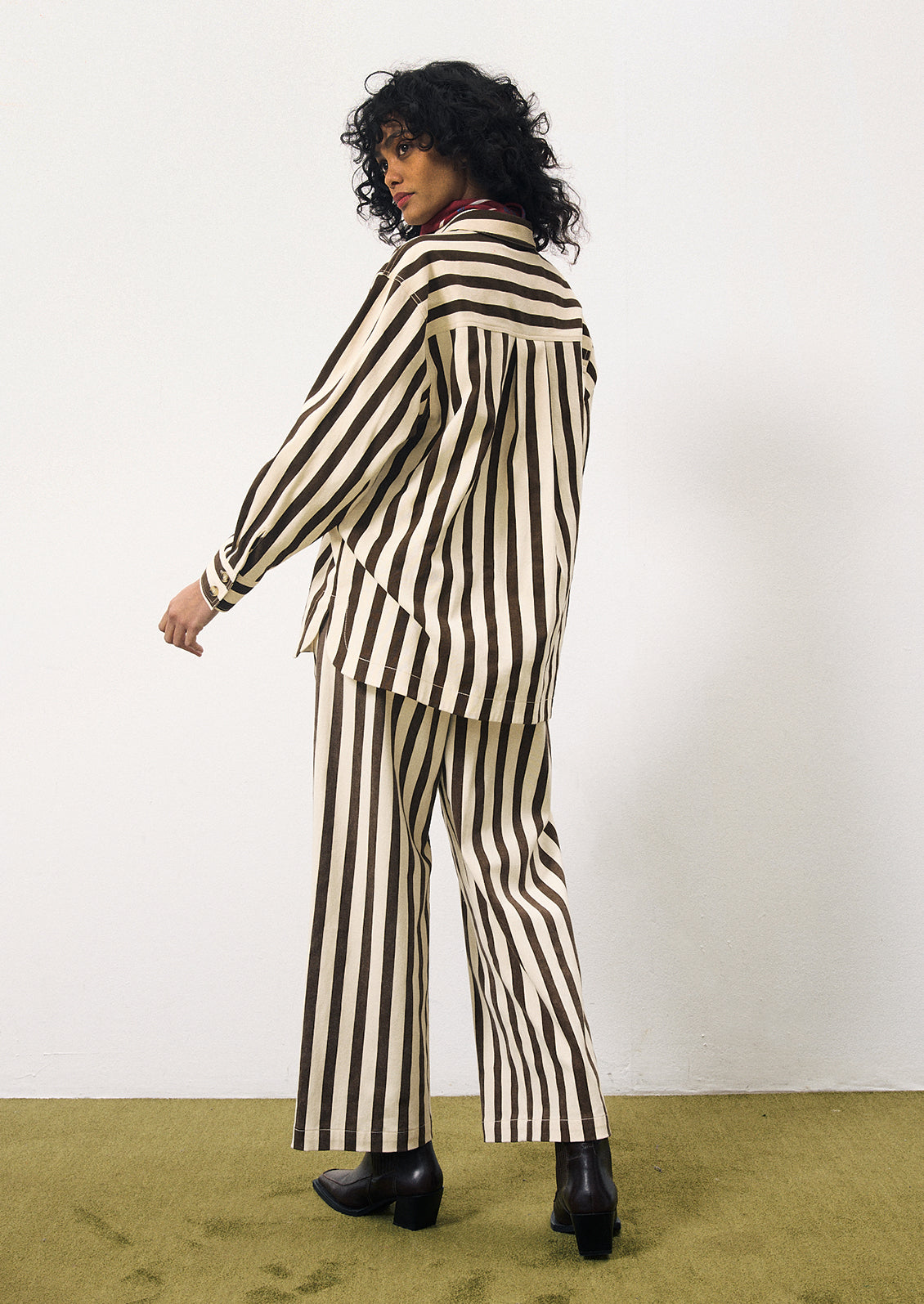 A woman wearing a pair of pants with thick vertical brown stripes on cream.