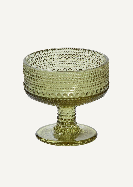 A coupe glass in olive green glass with round, vintage-style beaded texture.