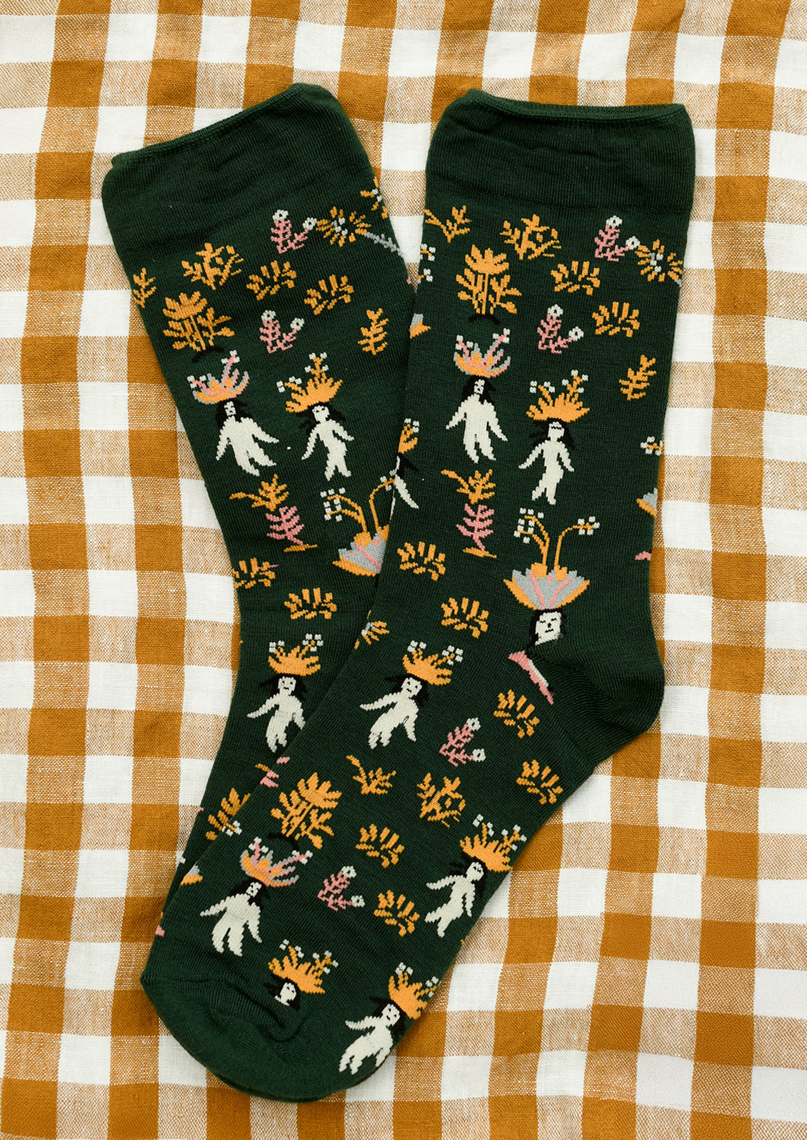 A pair of dark green socks with whimsical woman and flower print.