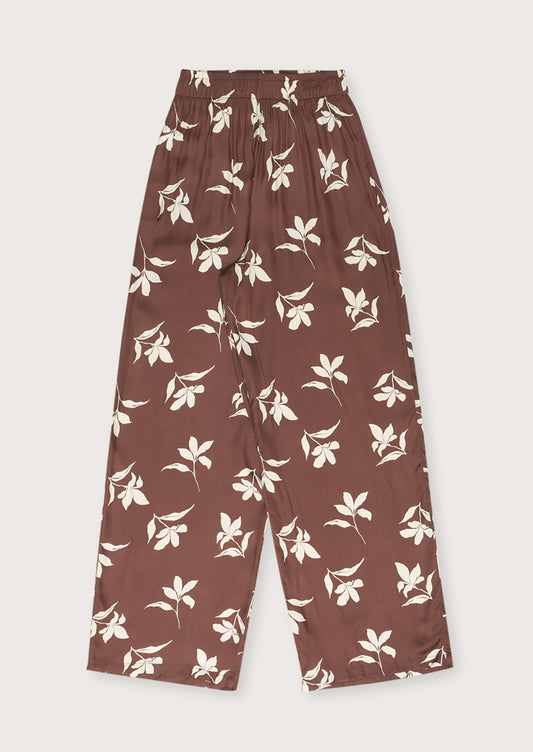 A pair of brown silky trousers with white floral print.