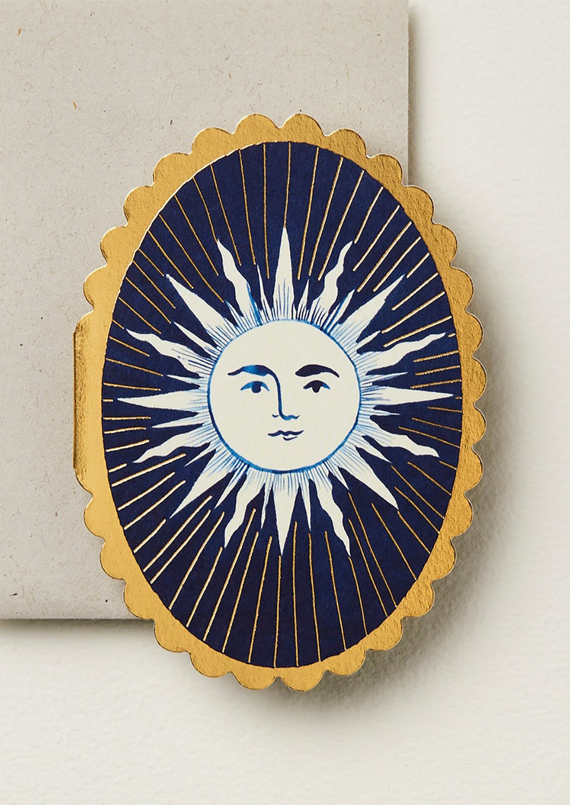 An oval shaped card with sun print and scalloped edges.