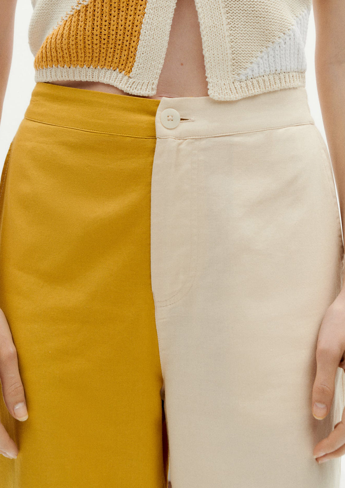A pair of pants with one leg in yellow and one leg in cream.