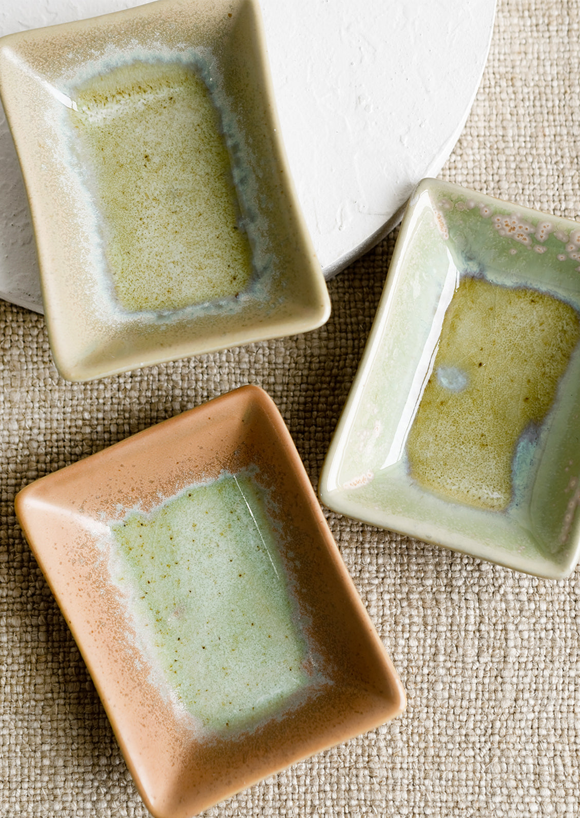 Rectangular ceramic sauce dishes in turquoise, green and brown varied glazes.