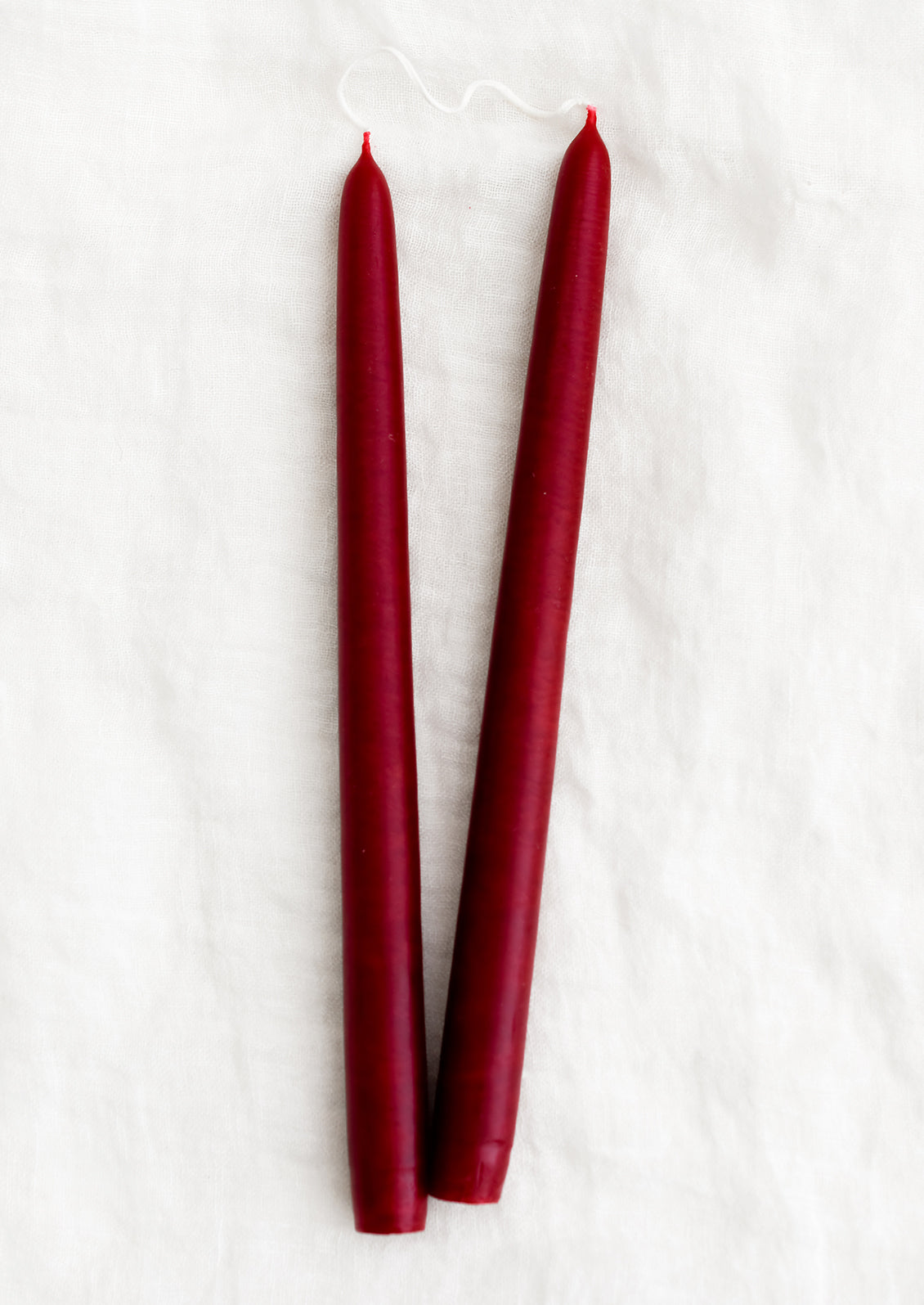 A set of 2 taper candles in the color ruby