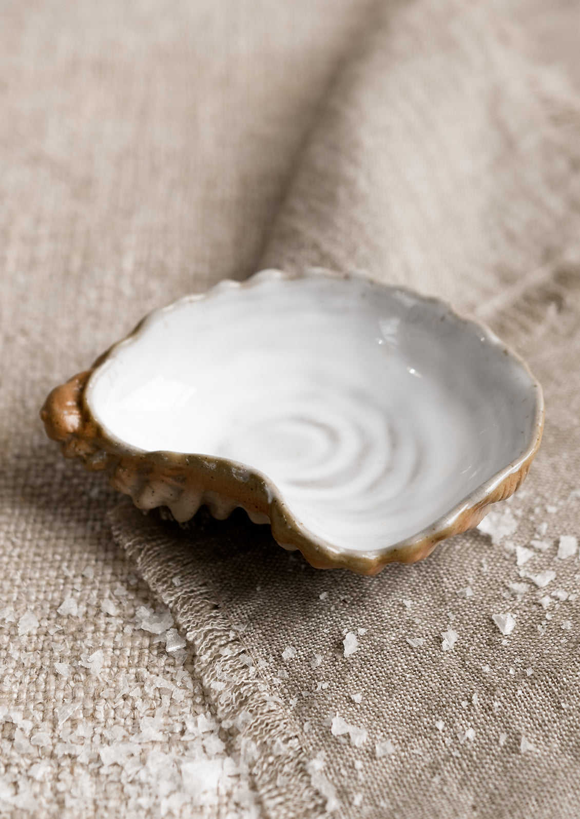 A small ceramic serving dish in shape of an oyster shell.