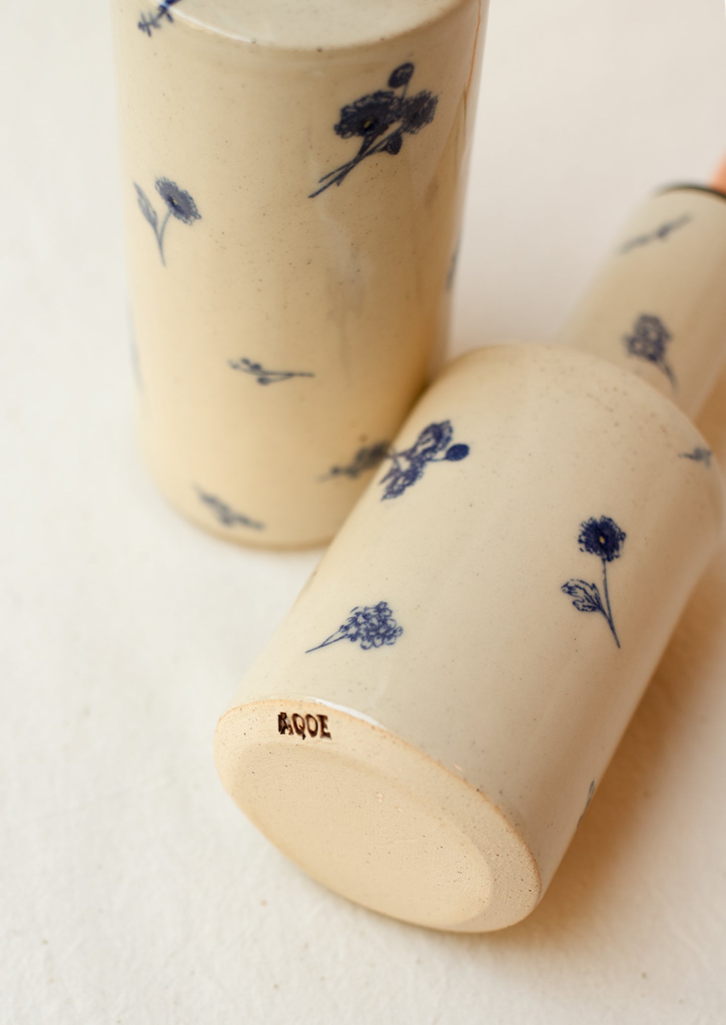 A pair of short and tall ceramic pouring bottles with blue floral pattern.