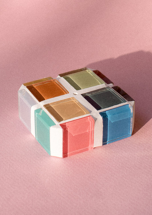 A square cube shape incense holder made up of multicolor glass tiles.