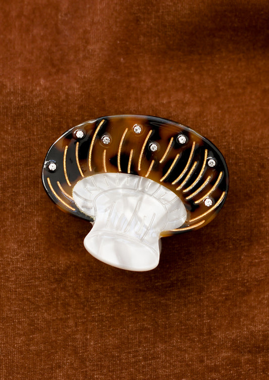 A hair claw in the shape of a brown mushroom with crystal detailing.