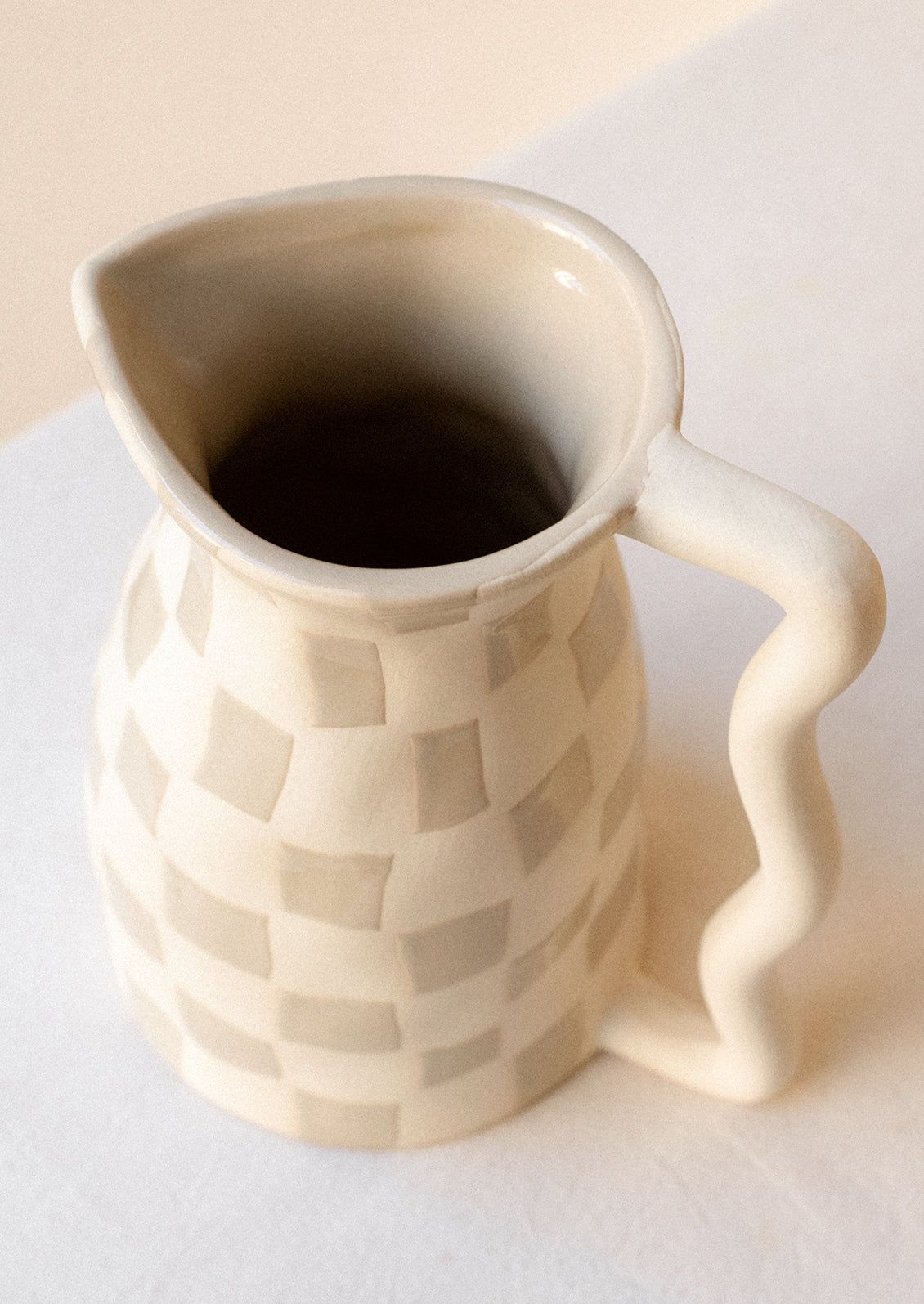 A white ceramic pitcher with taupe checker pattern.