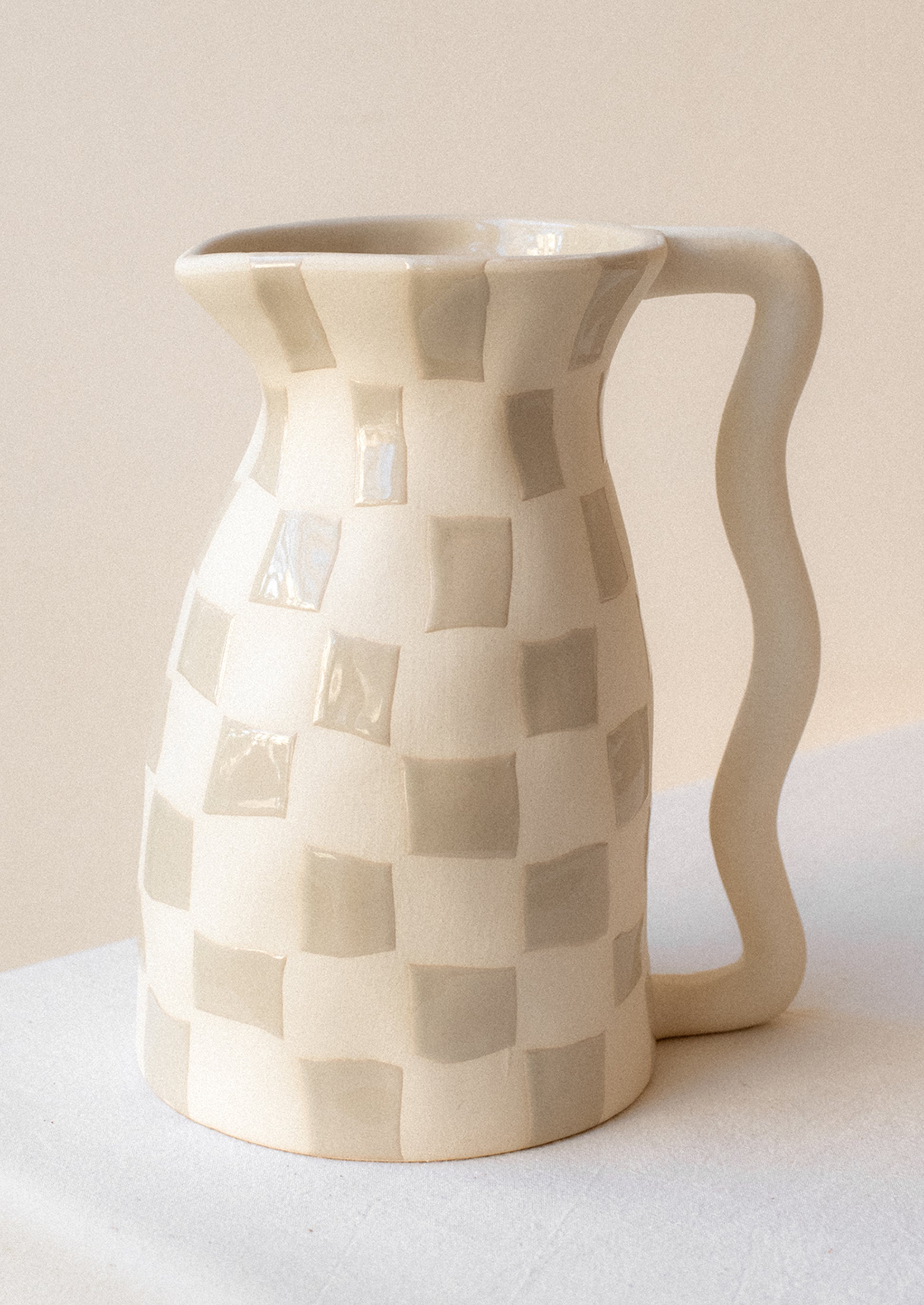 A white ceramic pitcher with taupe checker pattern.