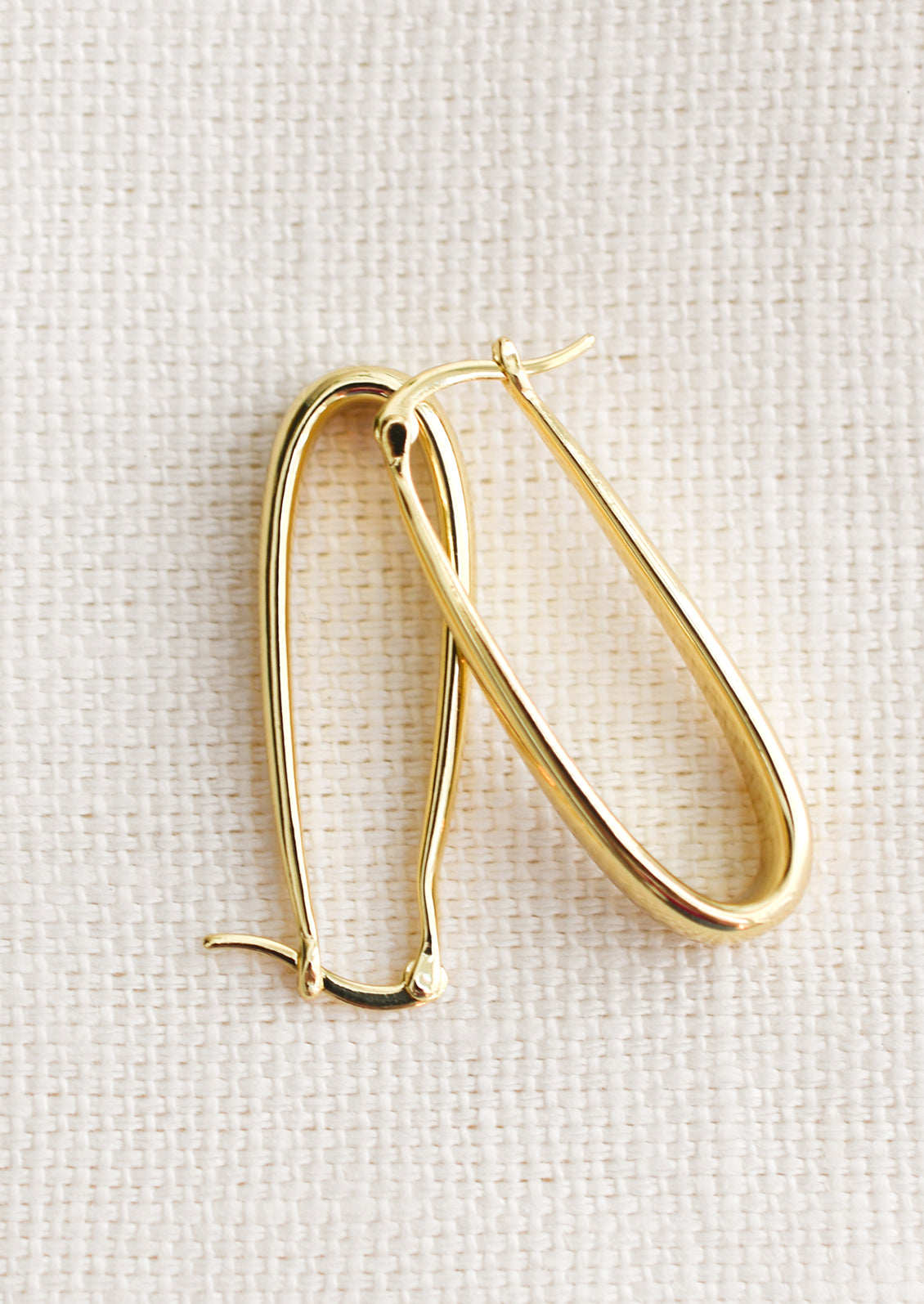 A pair of oblong hoop earrings with subtly tapered thickness, in gold.