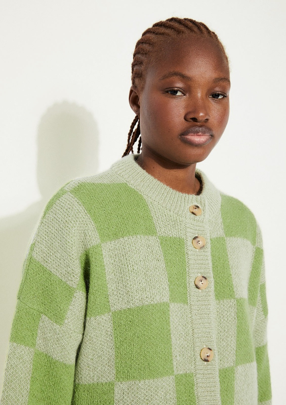 A woman wearing a checkered cardigan in two-tone green.