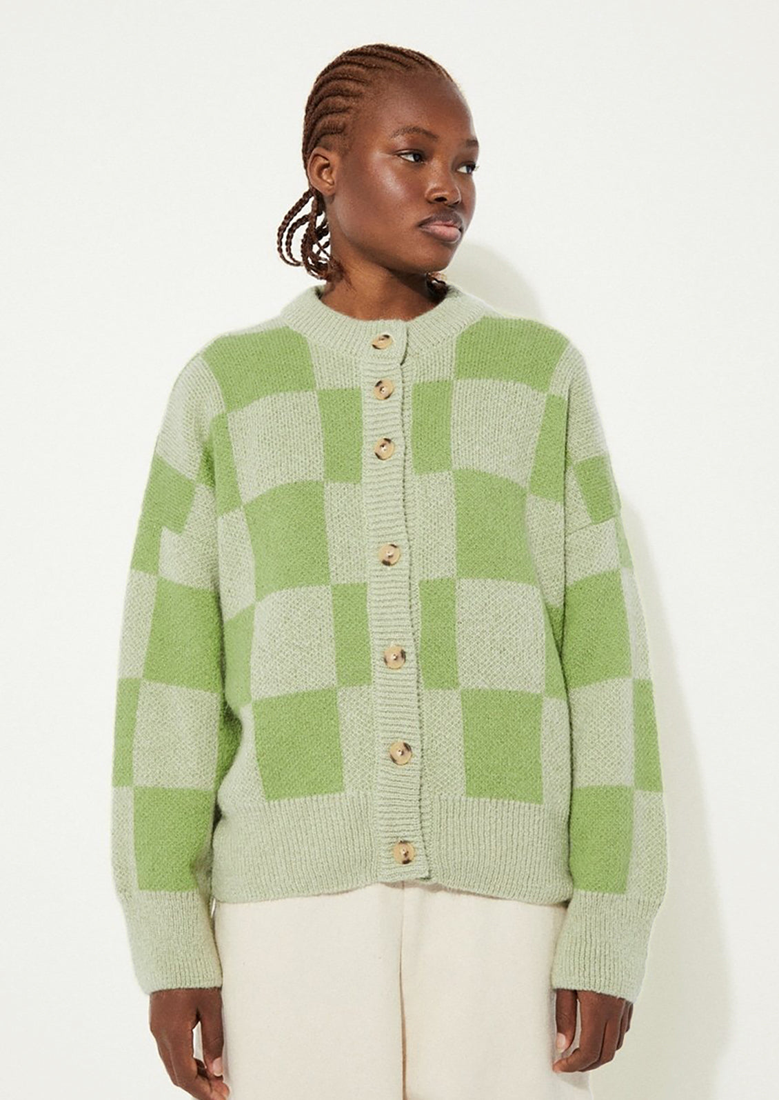 A woman wearing a checkered cardigan in two-tone green.