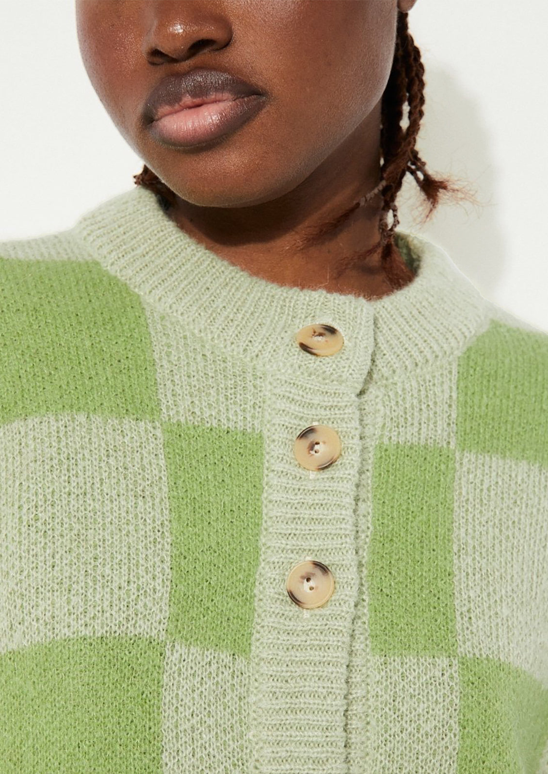 A woman wearing a checkered cardigan in two-tone green.