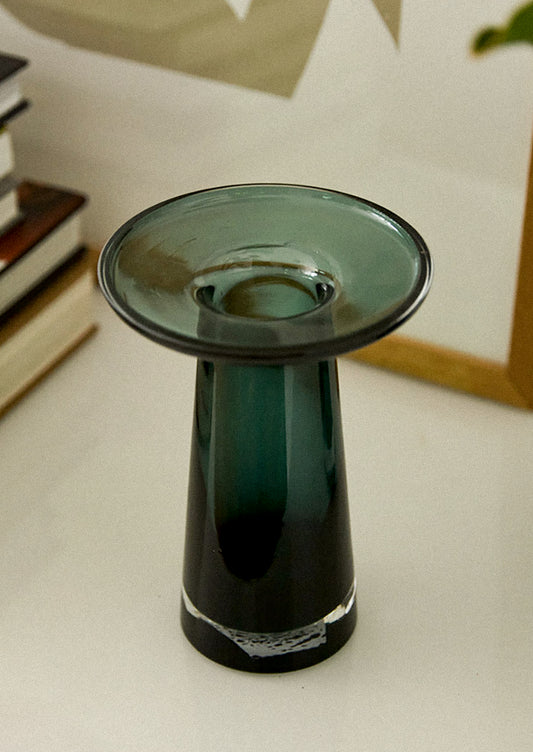 A glass vase in dark teal color, with round, saucer-like top.