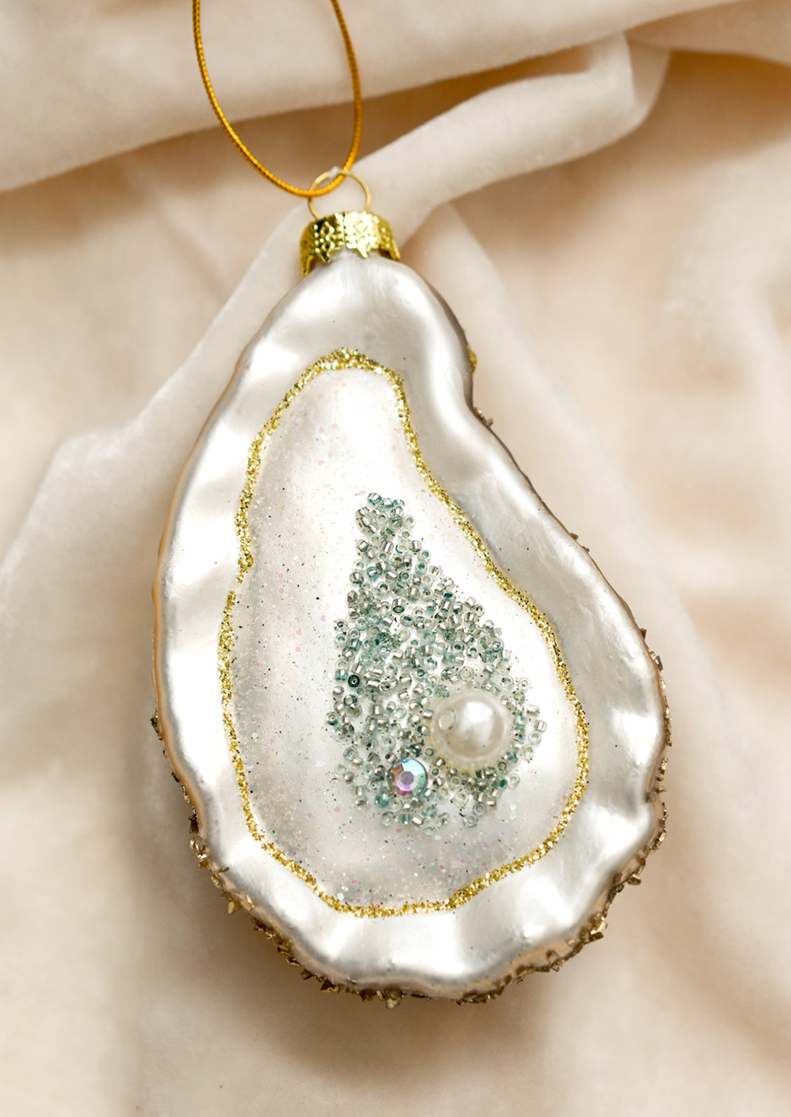 Glass oyster half shell ornament with pearl detail.