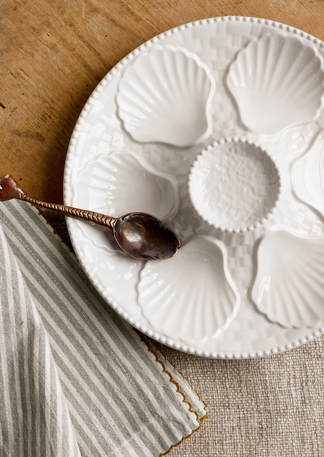 A glossy white ceramic plate with shell design.