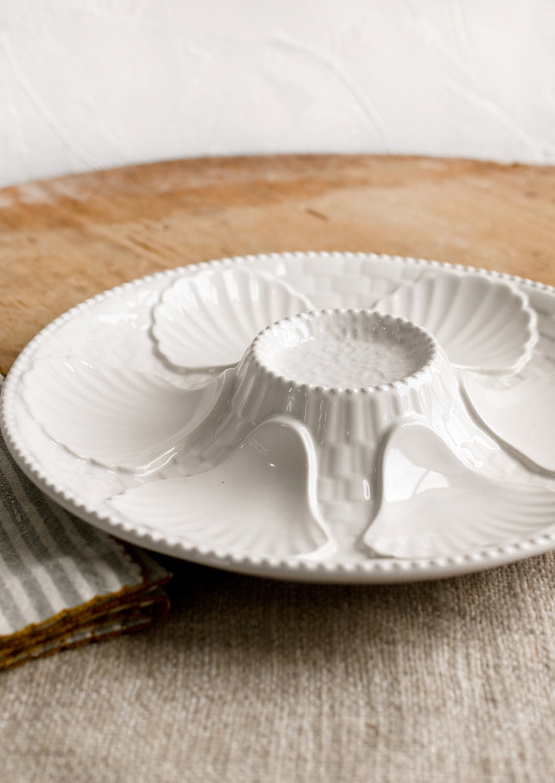 A glossy white ceramic plate with shell design.