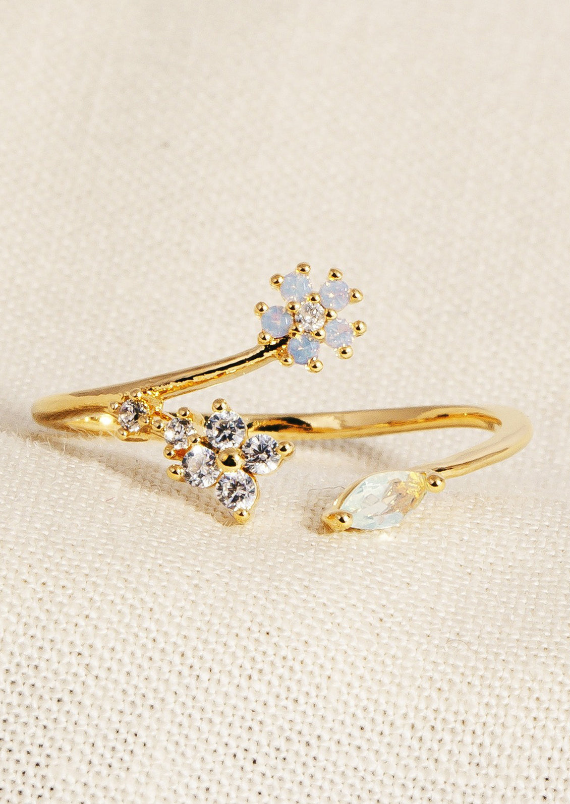 A gold ring with open front, with periwinkle flower and clear crystal flower.