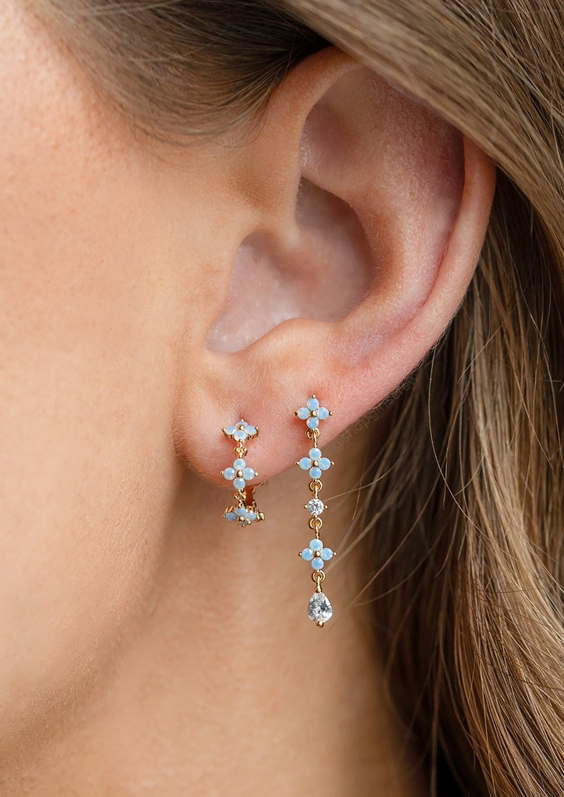 A person wearing a pair of periwinkle blue floral earrings.