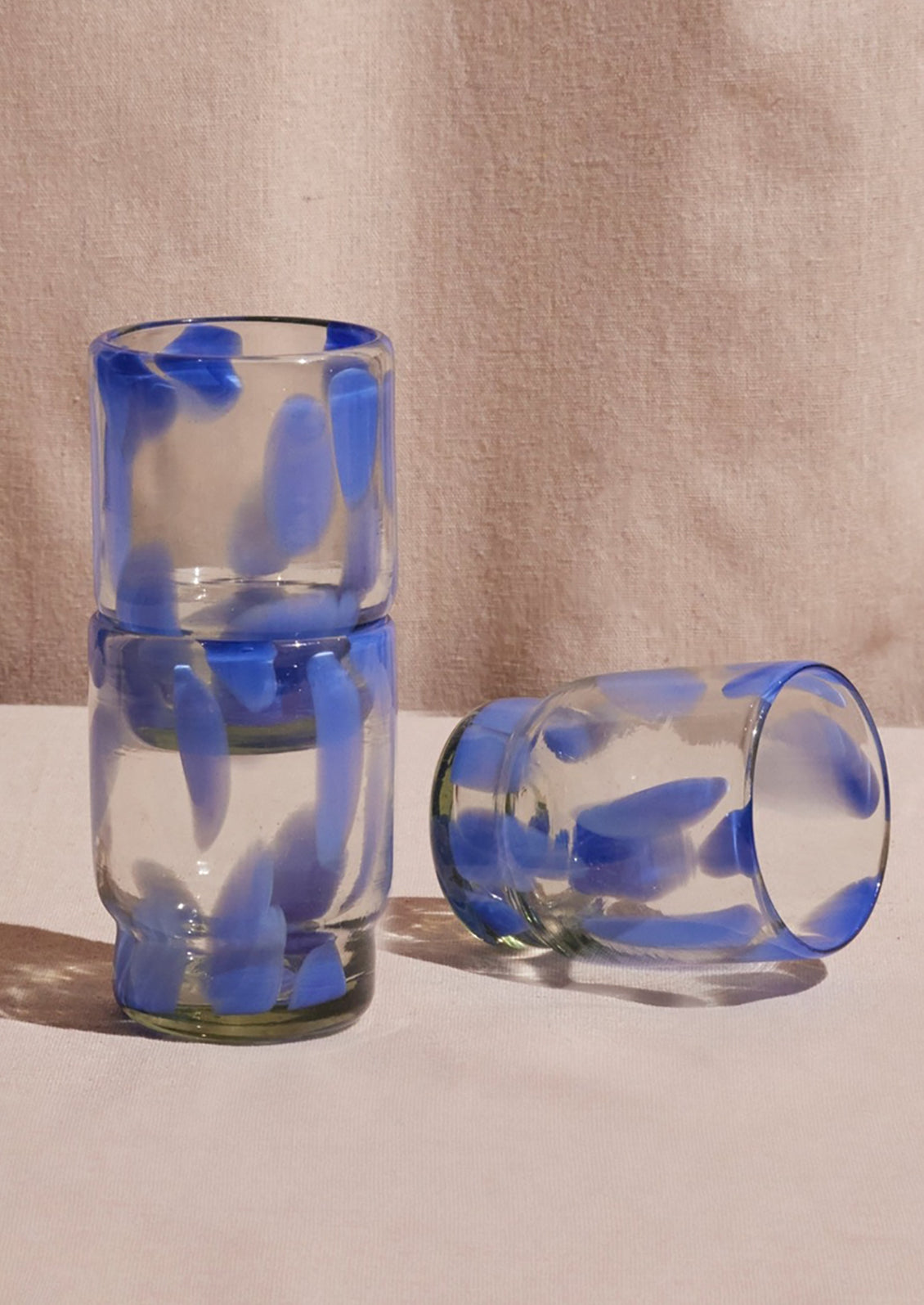 Stackable recycled glass tumblers with large periwinkle speckle pattern.