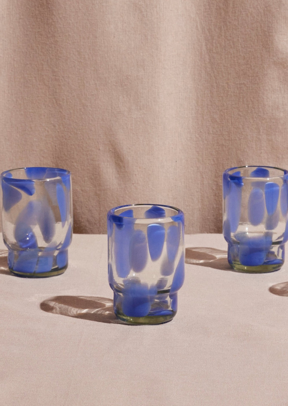 Stackable recycled glass tumblers with large periwinkle speckle pattern.