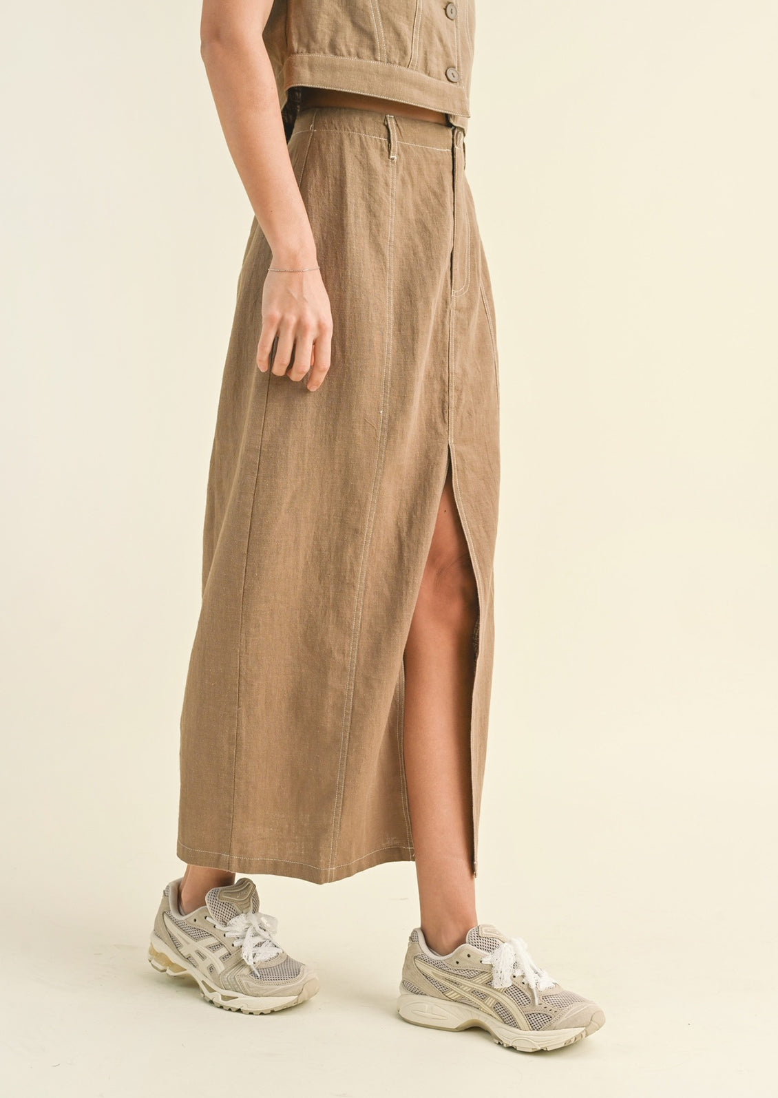 Woman wearing tan cotton midi skirt and sneakers. 