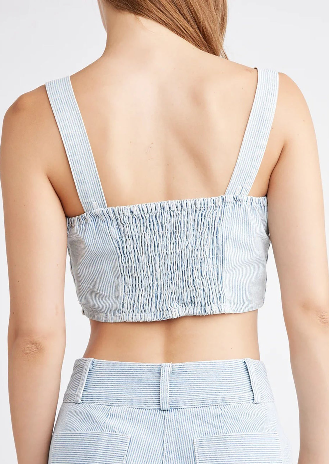 A woman wearing a square neck crop top with smocked elastic back.